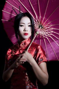Frau im Rotem Kimono mit einem Lilanem Schirm. Schlichte Kimono Muster sind zu sehen.