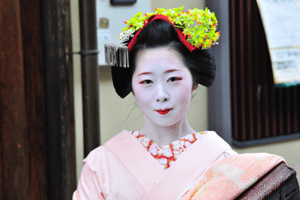 Geisha Kimono in Pink mit grünem Haarschmuck lächelnd