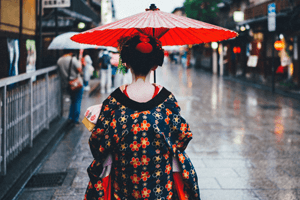 Geisha Kimono mit Rotem Schirm von hinten auf der Straße