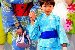 Kimono mit Libellen muster getragen von einem kleinen Jungen. Er hällt die Hand seiner Mutter.