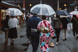 Paar in Kimono unter transparentem Regenschirm von hinten.