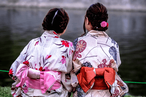 Zwei Frauen im Kimono mit Obi schleifen von hinten