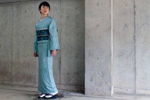 Frau im Blauen Iro Muji Kimono vor einer Steinwand.