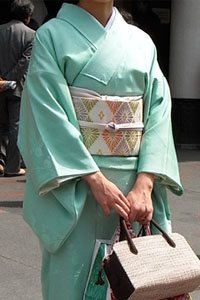 Frau in Türkis Iro Muji Kimono mit Handtasche.